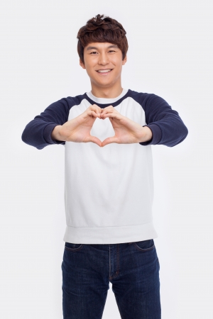 Young Asian man showing heart shape isolated on white background. の写真素材