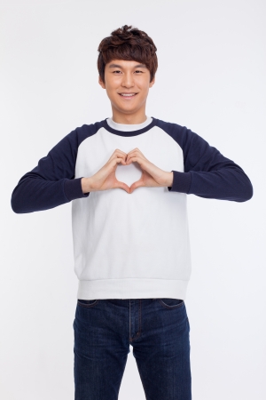 Young Asian man showing heart shape isolated on white background. の写真素材