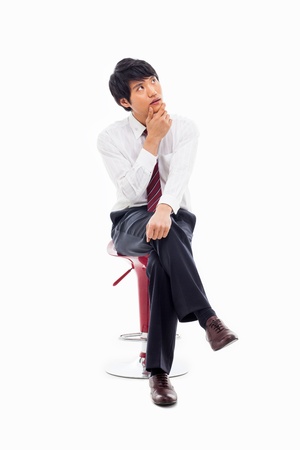Thinking Young Asian business man sitting on the chair isolated on white background. の写真素材