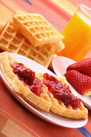 Waffles with the jam on plates with the glass of orange juiceの写真素材