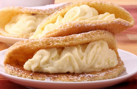 Cream cakes in the shape of omelets on platesの写真素材