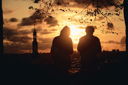 TALLINN, ESTONIA - SEP 14, 2019: Two people sitting together at sunrise at Toompea Hill in Tallinn...