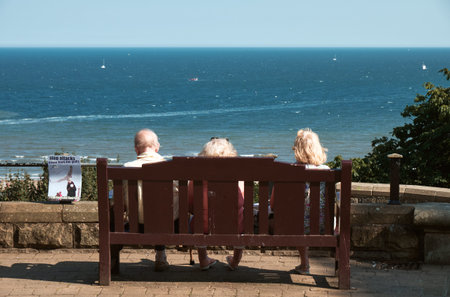 SCABOROUGH, UK - SEP 2, 2018: Old people sitting on a bench near the sea at Scaborough, UKのeditorial素材