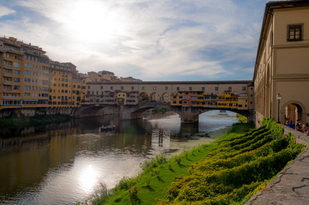 A serene view of the historic Ponte Vecchio bridge and the Arno River in Florence, Italy. Vibrant reflections on the water create a picturesque scene.のeditorial素材