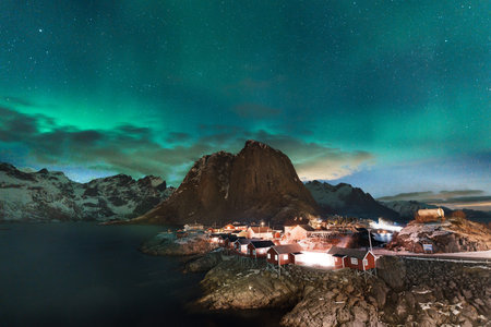 Northern lights over Hamnoy in Lofoten Island with mountains and sea.