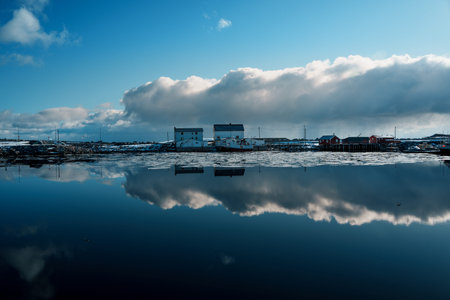 Scenic view of a coastal village with snow-capped mountains in the background at sunset.の写真素材