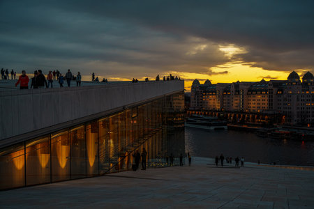 Oslo, Norway - Apr 13, 2024: A landscape of Oslo Opera House with people walking and relax around the area. The scene is set during twilight.の写真素材