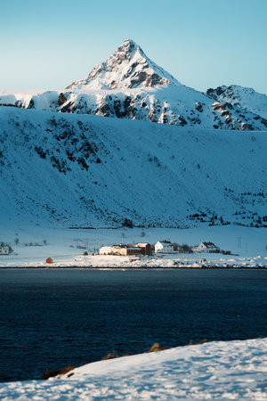 Stunning winter landscapes around Leknes in Lofoten, Norway, featuring snow-covered mountains, calm water reflections, and coastal roads at sunset.の写真素材
