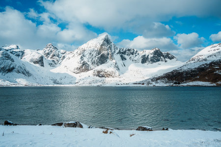 Scenic roadside views in Lofoten, Norway featuring dramatic snow-covered mountains and Arctic fjord.の写真素材
