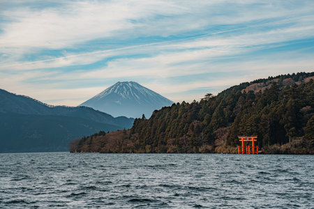 Scenic view of a traditional torii gate standing in a lake with forested hills in the background.の写真素材
