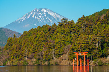 Peaceful morning scene in Hakone, Japan, featuring Lake Ashi, a red torii gate, forested hills, and majestic Mount Fuji.の写真素材