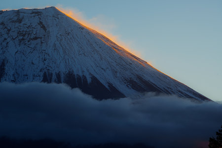 Close up of Mount Fujiâs sunrise glow with snowcapped peaks and drifting clouds.の写真素材