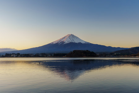 Perfect reflection of Mount Fuji on the calm waters of Lake Kawaguchiko at sunrise.の写真素材