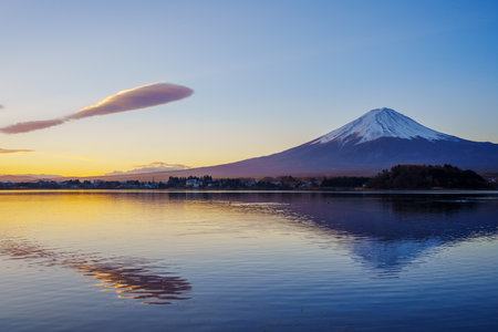 Dramatic sunset sky with lenticular clouds reflecting on Lake Kawaguchiko, featuring Mount Fuji.の写真素材
