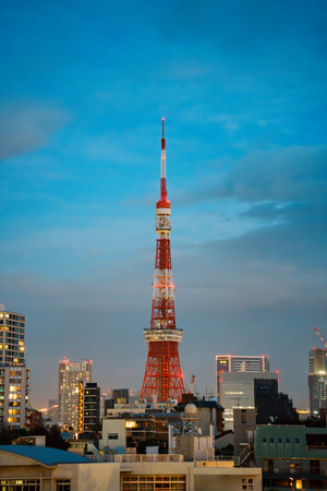 Tokyo Tower stands prominently amidst a cityscape of modern skyscrapers against a twilight sky.の写真素材
