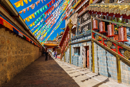 Shangri-La, China - Oct 21, 2024: Architecture of Songzanlin Monastery with colorful prayer flags fluttering against a clear blue sky.の写真素材