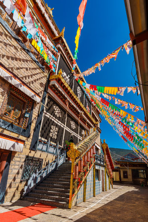 Architecture of Songzanlin Monastery with colorful prayer flags fluttering against a clear blue sky.の写真素材