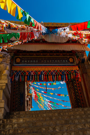Architecture of Songzanlin Monastery with colorful prayer flags fluttering against a clear blue sky.の写真素材