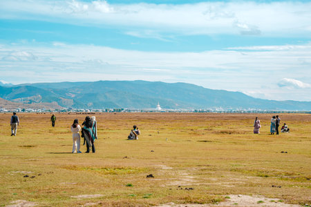 A wide, panoramic landscape showing the immense scale of the Yila Grassland and Napahai Lake, with...