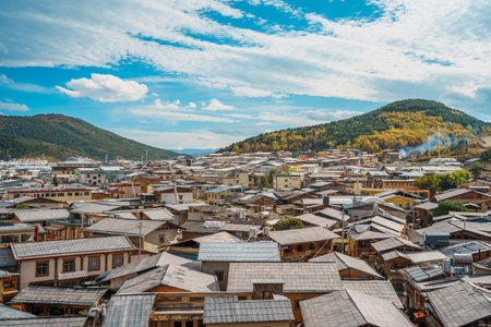 Expansive high-angle view over the traditional tiled roofs of Shangri-La's old town, with mountains behind.の写真素材