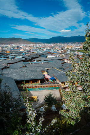 Expansive high-angle view over the traditional tiled roofs of Shangri-La's old town, with mountains behind.の写真素材