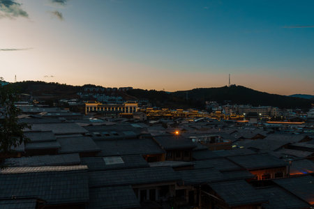 Dramatic pink and blue sunset clouds over the historic rooftops and mountains of Dukezong Ancient Town in Yunnan, China.の写真素材