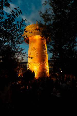 Golden light bathes the giant prayer wheel of Dafo Temple on Guishan Hill against a deep blue twilight sky in Yunnan, China.の写真素材