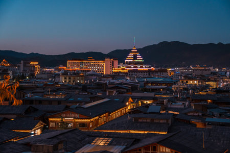 Dramatic orange and blue dusk with clouds over the historic rooftops and mountains of Dukezong Ancient Town in Yunnan, China.の写真素材