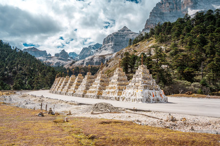 A line of traditional white Buddhist stupas (Shambhala Pagodas) in a stunning mountain landscape in...