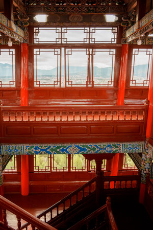 Scenic view of Lijiang city and surrounding mountains framed through a traditional Chinese window in...