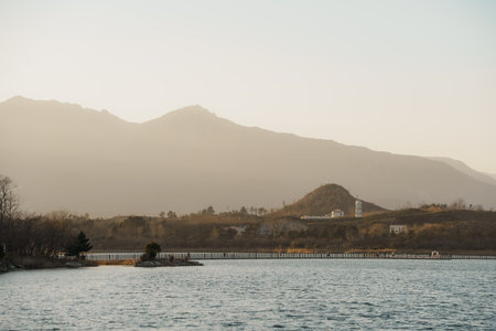 Warm sunset light over rippling water and layered mountain silhouettes from a lakeside viewing bench at Yeongrang Lake, Sokcho, South Korea.の写真素材