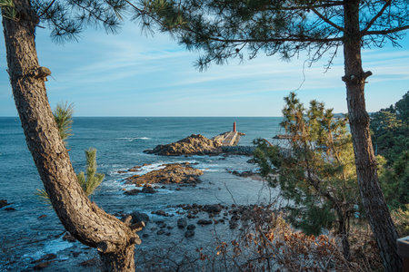 Elevated view of Naksan Beach pier leading to a bright red lighthouse, with tetrapods and rocks...