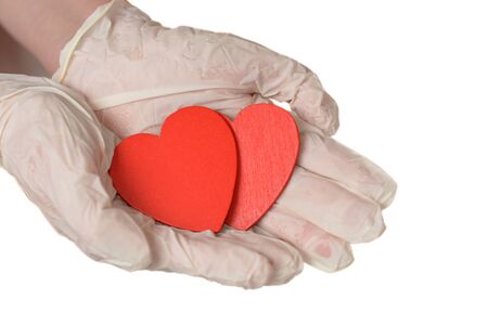 Two red hearts in hand with rubber gloves isolated on whiteの写真素材