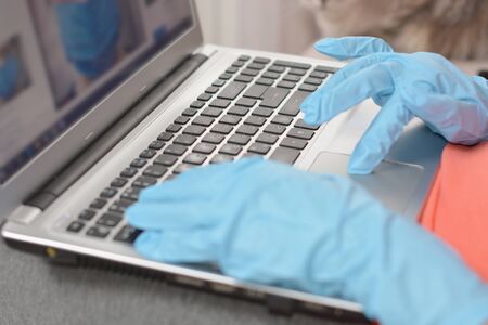 hand in blue rubber glove working at notebookの写真素材