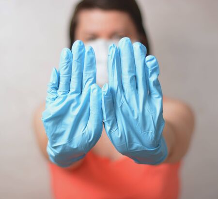 Woman with blue rubber glove make stop gesture. Soft focused.の写真素材