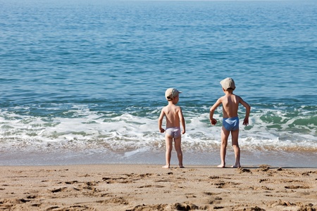 Summer vacations - two little child boy brothers walking sea sand beachの写真素材