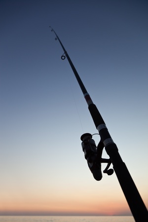 Fisherman sport hobby fishing rod or spinning reel on sea beach sunsetの写真素材