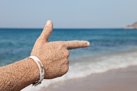 Summer vacations - woman hand index finger pointing direction to sea sand beachの写真素材