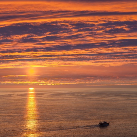 Summer vacations - water travel ship or boat sailing blue sea waves on sunsetの写真素材