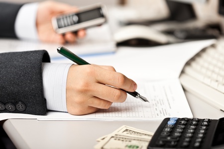 Working business man hand pen writing paper document at office workplaceの写真素材