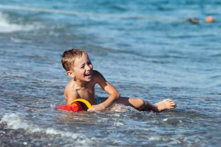 Summer vacations - little smiling child boy playing on sea sand beachの写真素材