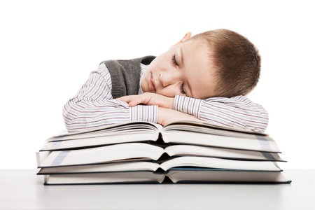 Tired child boy sleeping on education reading books at school deskの写真素材