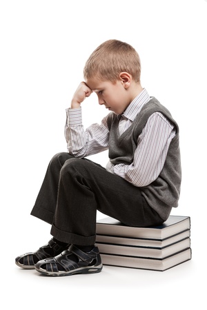 Puzzled or perplexed thinker child boy sitting on education reading books stackの写真素材
