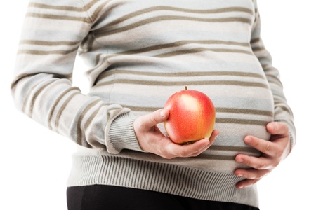 Pregnancy and new life concept - beauty pregnant woman hand holding red raw ripe apple fruitの写真素材