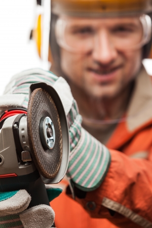 Construction building engineer or manual worker man in safety hardhat helmet hand holding electric angle grinder disk tool white isolatedの写真素材