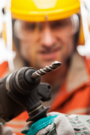Construction building engineer or manual worker man in safety hardhat helmet hand holding electric hammer drill tool white isolatedの写真素材
