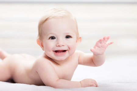 Little cute smiling newborn baby child boy hand gesturing hello or goodbye signの写真素材