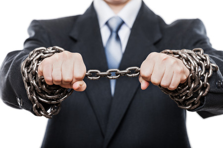 Business problems and failure at work concept - businessman struggles metal chain knot tied hands...
