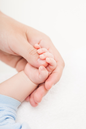 Loving mother holding newborn baby child little hand with small fingersの写真素材