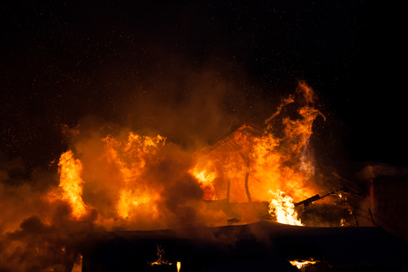 Arson or nature disaster - burning fire flame on wooden house roofの写真素材